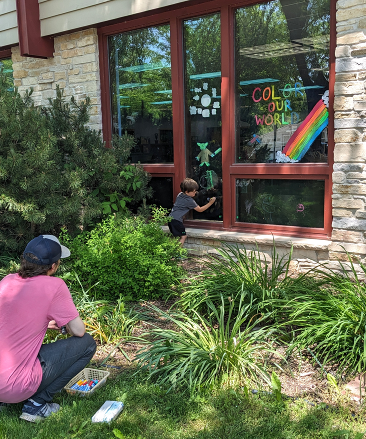 Adult and child adding window paint designs to library window image