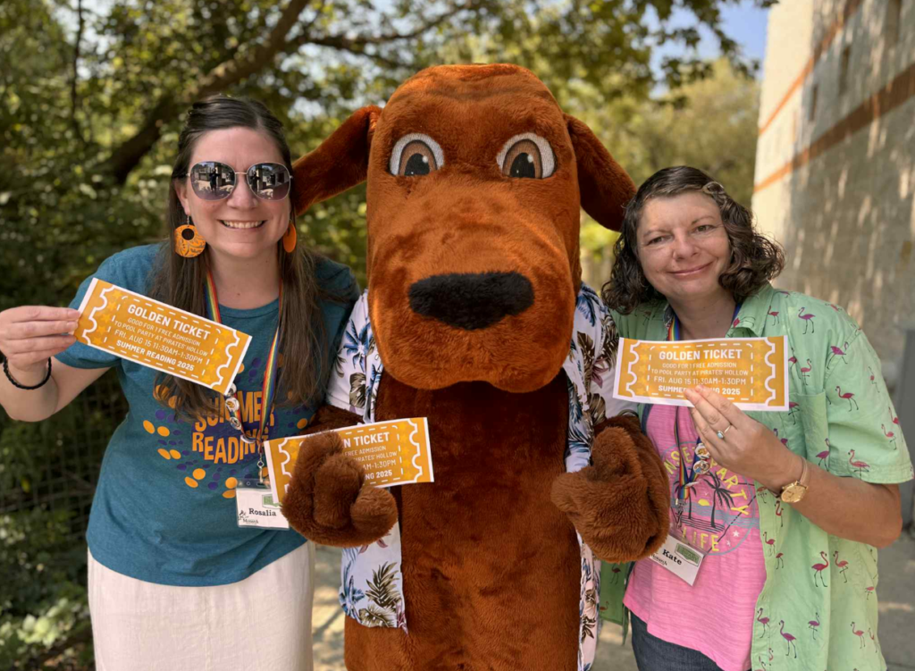 Librarians holding golden tickets with Booker the Library Dog mascot in the middle